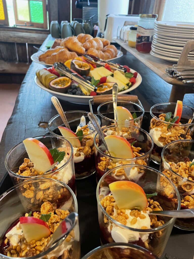 breakfast foods lined up on a table with crockery and cups in the background